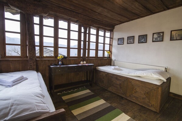 A rustic room with wooden walls and a large window. There is a bed, a desk, and a radiator. - Beautiful private villa for 5 people with WIFI, pets allowed and panoramic view (Selishte)