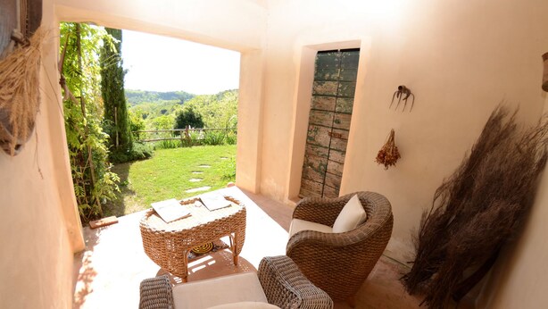 A cozy patio area with wicker furniture, a view of a lush garden, and a rustic wooden door. - Wonderful private villa with A/C, WIFI, private pool, TV, veranda, pets allowed and panoramic view (Aiale)