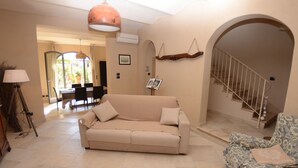 A living room with a beige sofa, a patterned armchair, a lamp, and a staircase. - Wonderful private villa with A/C, WIFI, private pool, TV, veranda, pets allowed and panoramic view (Aiale)
