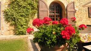 A stone building with a large potted plant of red flowers in front. - Private Villa with hot tub, private pool, A/C, WIFI, sauna, TV, patio, pets allowed, panoramic view (Grezzano)