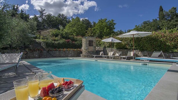 A swimming pool with lounge chairs and umbrellas, surrounded by greenery and stone walls. - Private Villa with hot tub, private pool, A/C, WIFI, sauna, TV, patio, pets allowed, panoramic view (Grezzano)