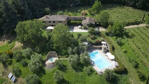 An aerial view of a property with a swimming pool, stone buildings, and vineyard. - Private Villa with hot tub, private pool, A/C, WIFI, sauna, TV, patio, pets allowed, panoramic view (Grezzano)