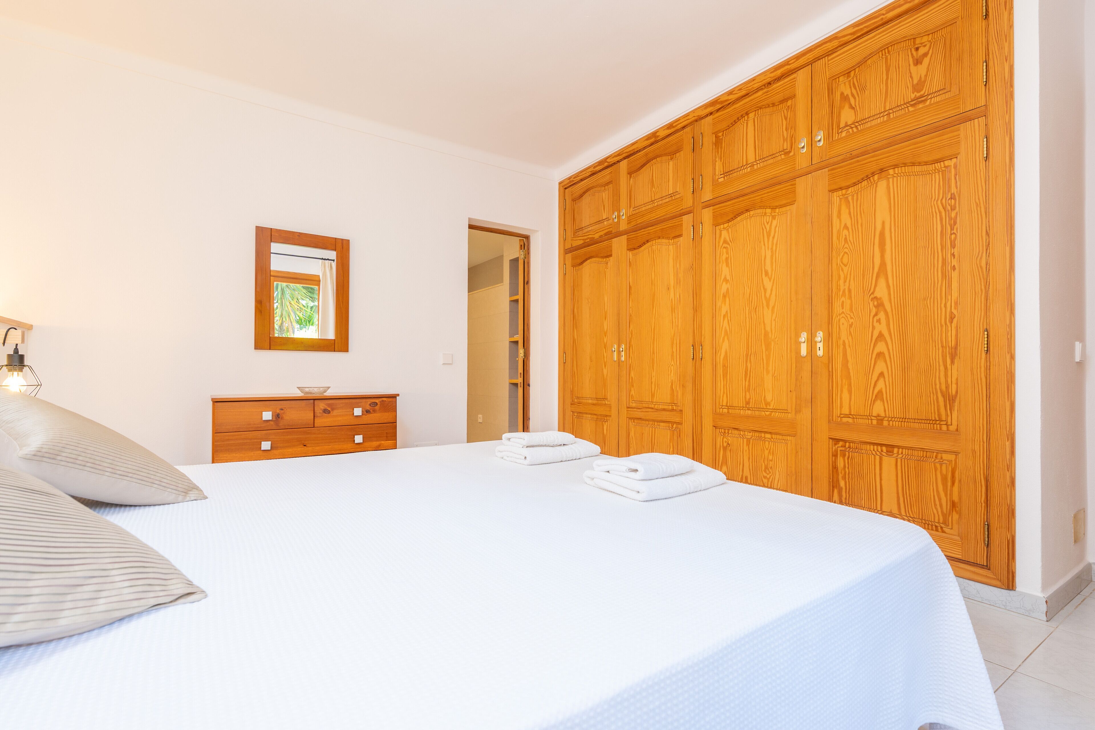 Une chambre à coucher avec un grand lit, une armoire en bois et une commode.