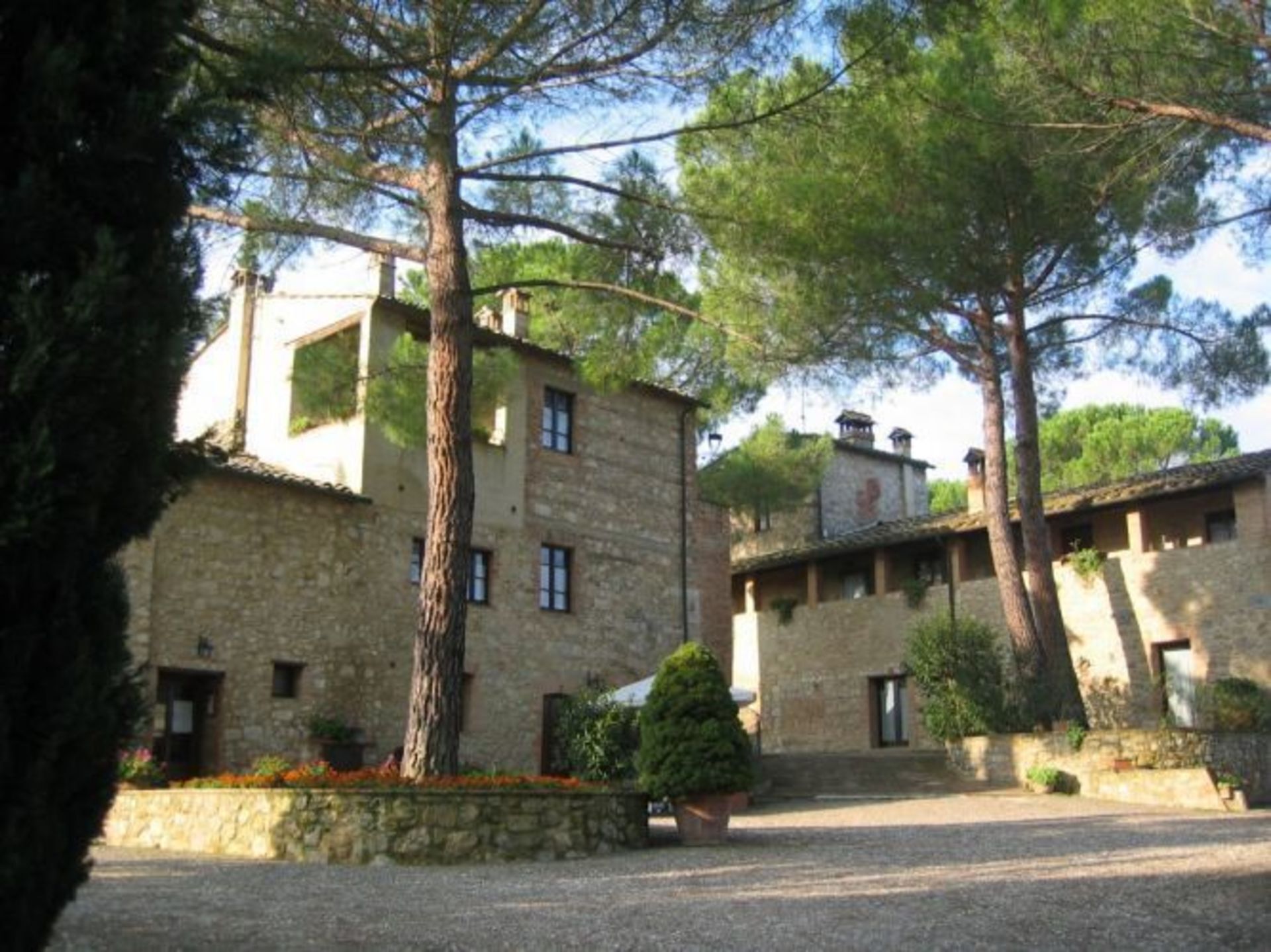 A stone building with a courtyard, surrounded by trees.