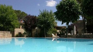 Una piscina azul cristalina rodeada de árboles y edificios de piedra.
