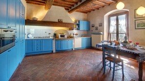 Cucina con mobili blu, pavimento in mattoni e soffitto in legno.