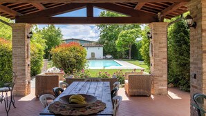 Un patio exterior con piscina, rodeado de muros de ladrillo y follaje.