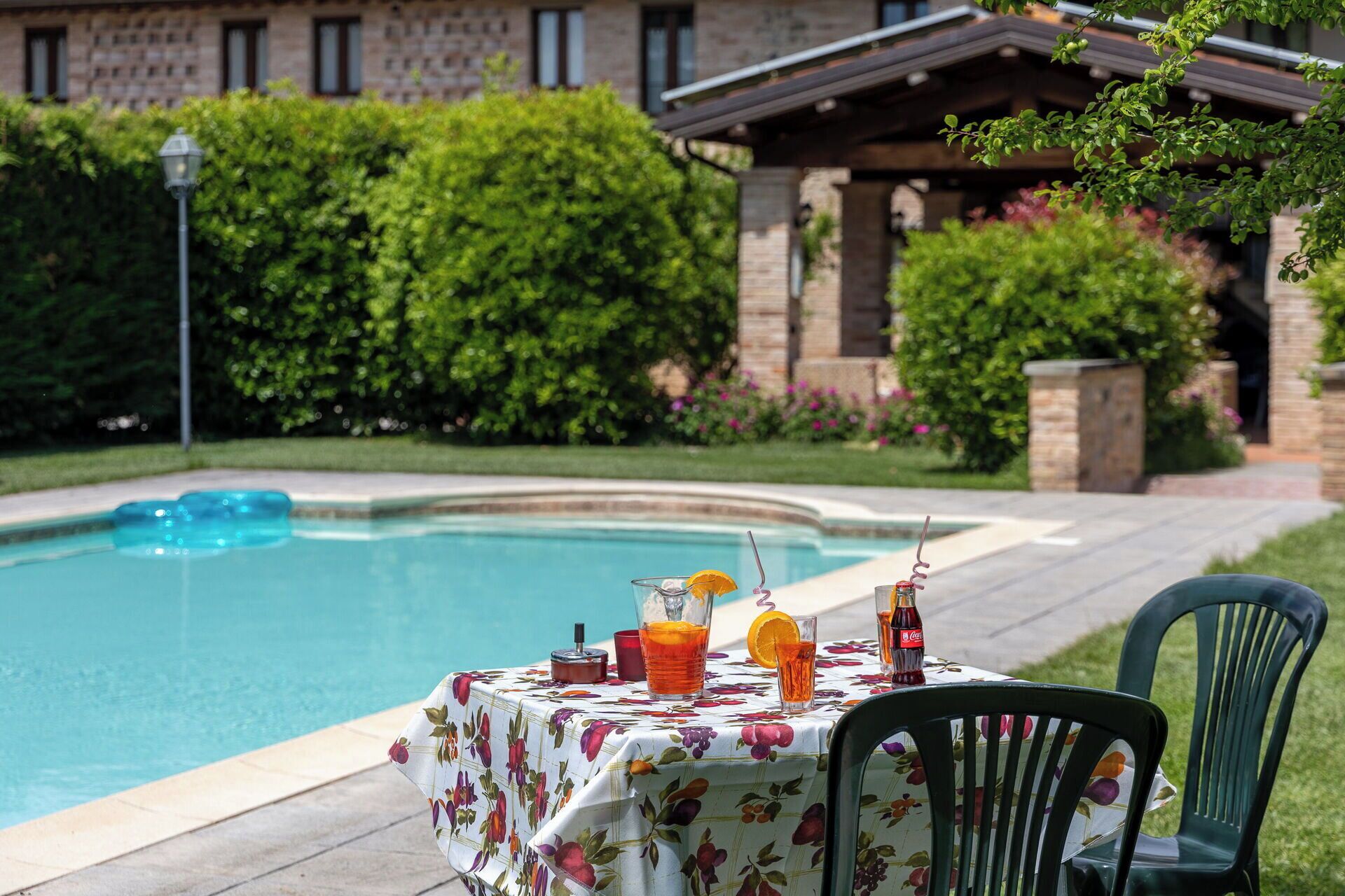 A poolside table with drinks, a chair, and a pool.