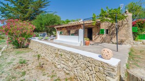 A stone-walled building with a tiled roof, a small patio area with lounge chairs, and a potted plant. - SA ROTA (DEN JOAN PORRERENC) - House with terrace in Montuïri. Free WiFi (Montuïri)
