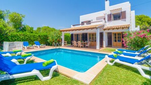 Een moderne villa met zwembad, terras en weelderige begroeiing.