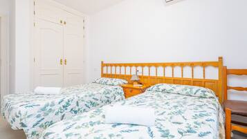A bedroom with two beds, a wooden headboard, a nightstand, and a white wardrobe.