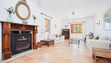Ein Wohnzimmer mit Kamin, weißen Sofas, einem Couchtisch und einem Fernseher.