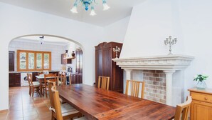 A spacious dining area with a large wooden table and chairs, a fireplace, and a view of the kitchen through an archway. - SA CORBAIA NOVA  - Villa with private pool in Arta. Free WiFi (Artà)