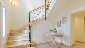 A staircase with a wooden handrail and a small round table with a floral arrangement. - SA CALETA - Villa with private pool in Cala Egos (Santanyi). Free WiFi (Santanyí)