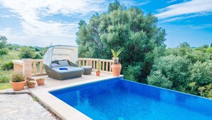 A swimming pool with a lounge area, potted plants, and a view of trees and hills. - CAN CANALS - Villa with private pool in Artà. Free WiFi. (Artà)