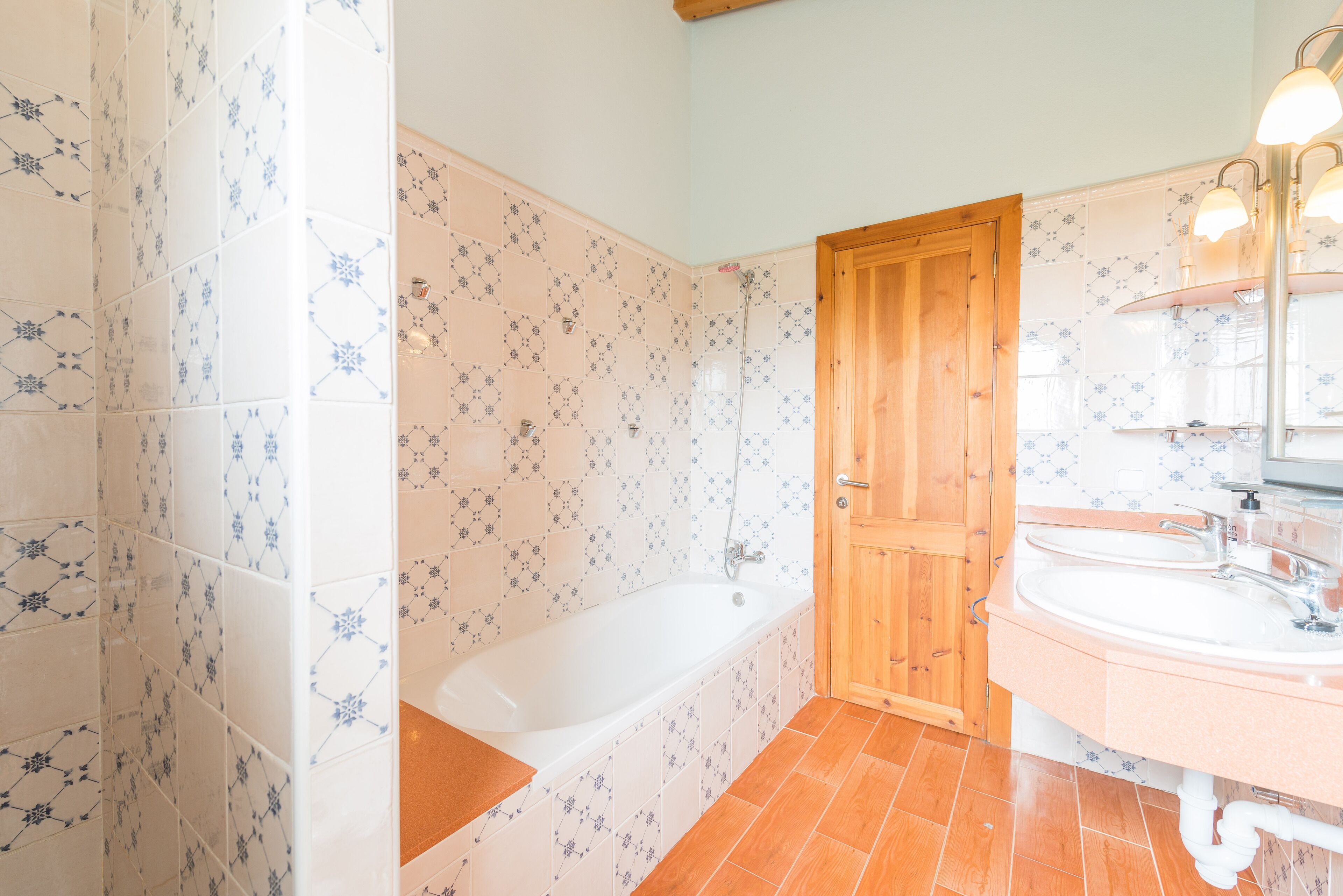 Une salle de bain avec une baignoire, une porte en bois et un lavabo avec un miroir.