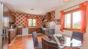 A modern kitchen with a glass dining table, wooden cabinets, and a view of greenery outside. - CAN CANALS - Villa with private pool in Artà. Free WiFi. (Artà)