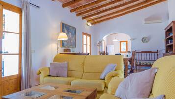 Una sala acogedora con un sofá amarillo, una mesa de centro de madera y techo de madera.