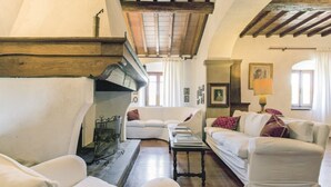 Una sala de estar acogedora con chimenea, dos sofás blancos, una mesita de centro y una lámpara.