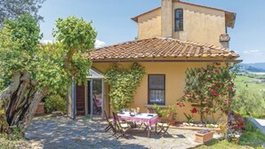 Una casa rústica con techo de tejas, un patio de piedra y una mesa lista para comer.