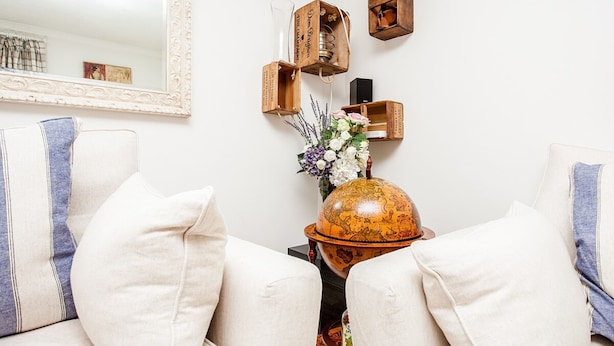 Uma sala de estar com um sofá branco, um globo e objetos decorativos em uma mesinha lateral.