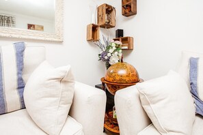A living room with a white sofa, a globe, and decorative items on a side table. - Stunning Spacious South London 1 Bed Apartment with Balcony (London)