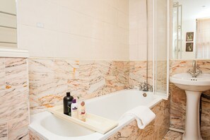 A bathroom with a bathtub, a sink, and marble tiles. - Charming Central London Flat (London)
