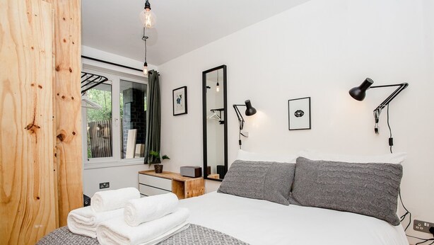 Une chambre moderne avec un grand lit, deux lampes de chevet, un miroir et une armoire en bois.