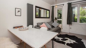 Un salon moderne avec une table en marbre blanc, un canapé gris et un tapis en peau de vache noir et blanc.