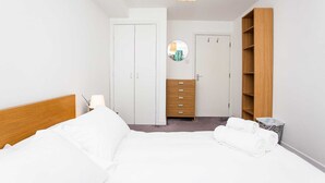 Et hotelværelse med en seng, et træskab, en kommode, et spejl og et lille bord med en lampe.