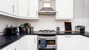 Et moderne køkken med hvide skabe, en sort bordplade, en gaskomfur og en ovn.