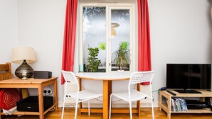 Et værelse med et træbord, to hvide stole, en lampe, et fjernsyn og en reol.