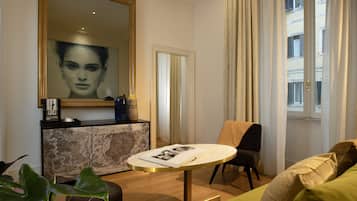 A modern living room with a round table, a sofa, a chair, a large mirror, and a window with curtains.