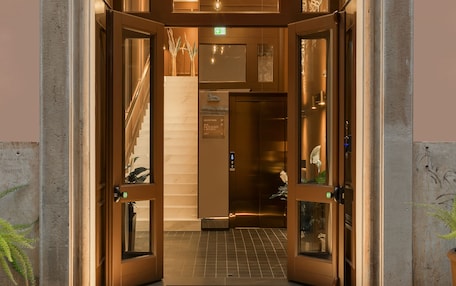 A hotel entrance with a stone facade, a staircase leading to the interior, and a reception desk.