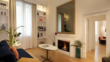 A living room with a fireplace, a sofa, a coffee table, and a bookshelf.