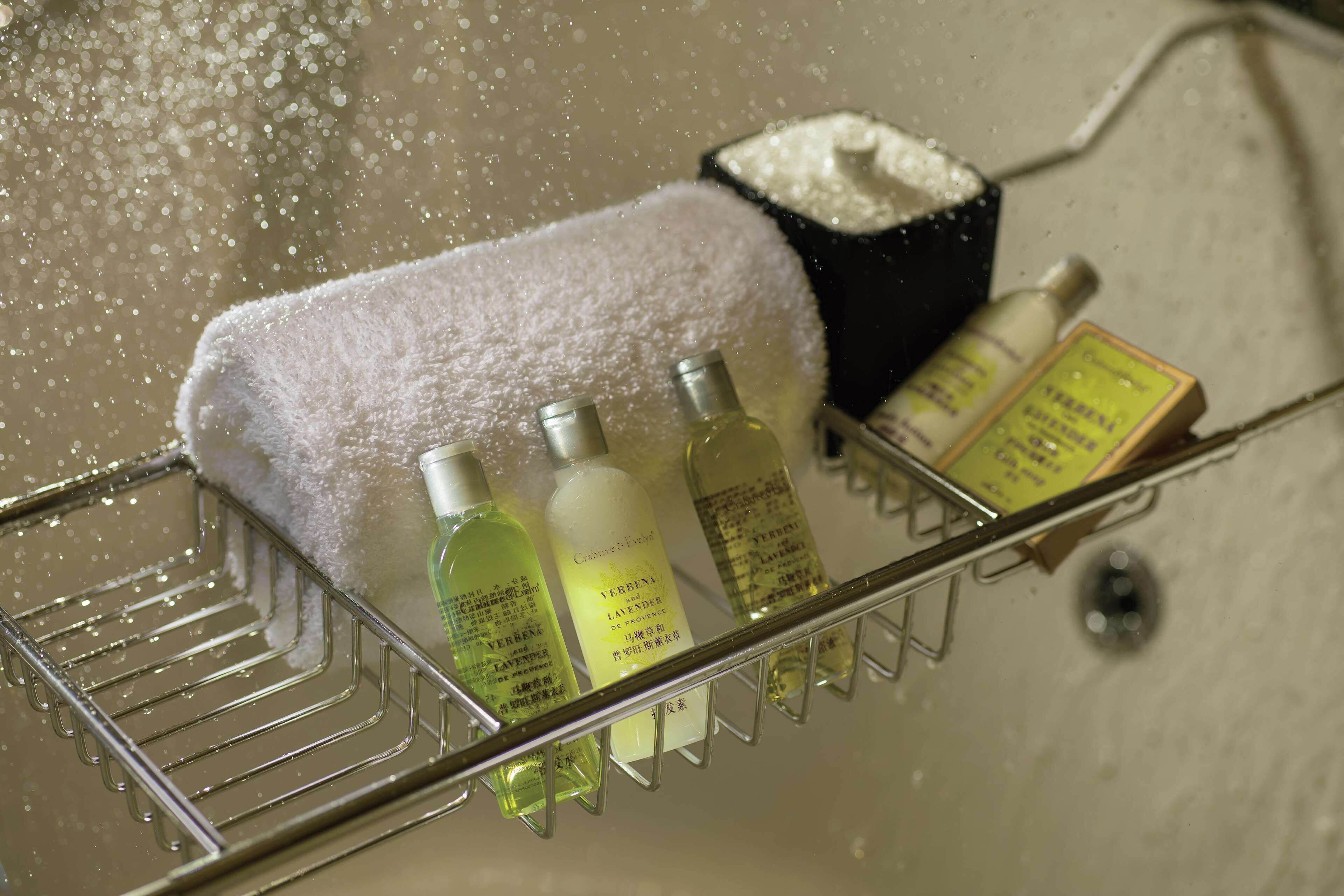 Un estante en el baño con una toalla blanca, dos botellas de crema y una barra de jabón.