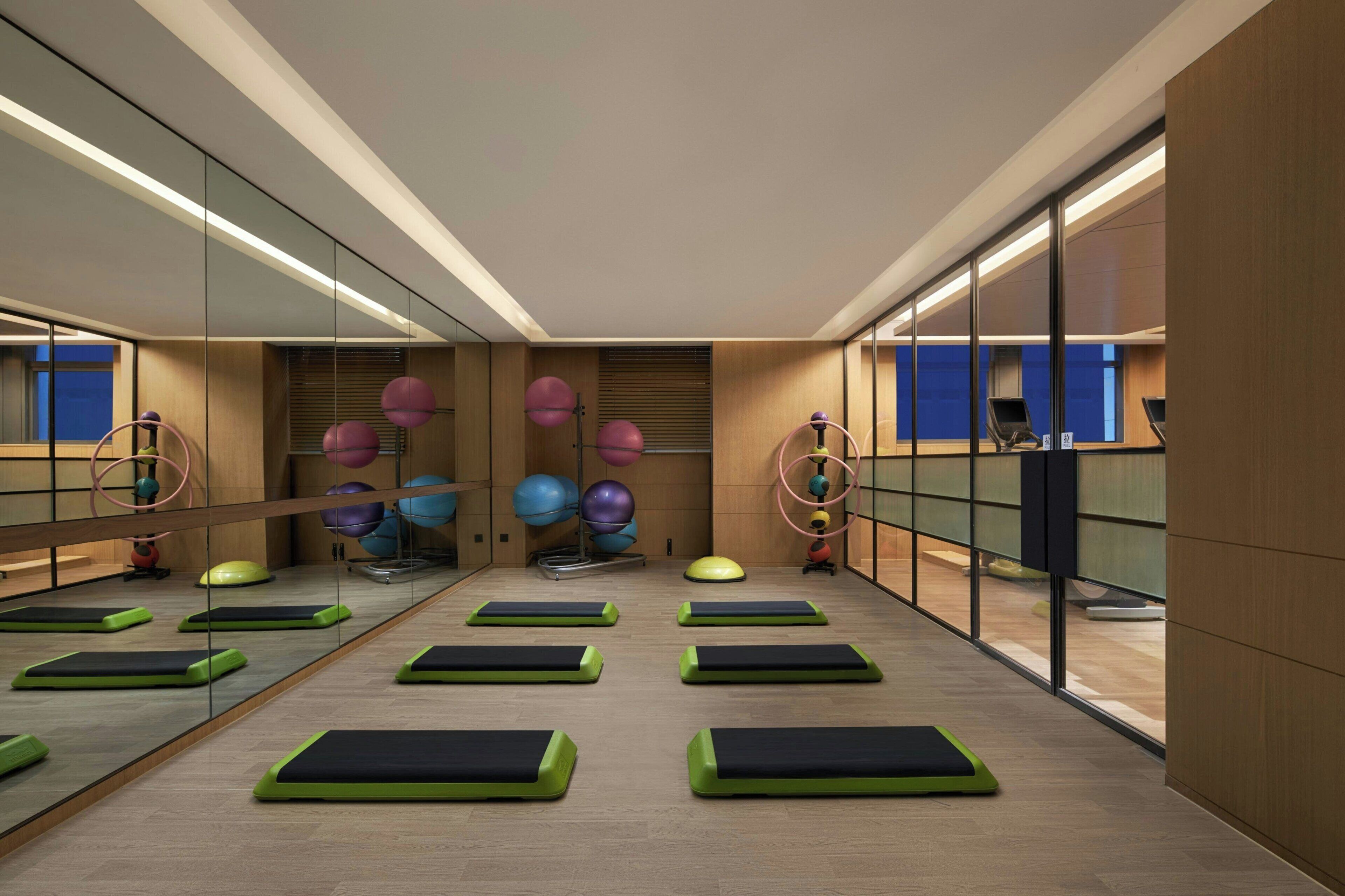 A modern fitness room with exercise mats, a variety of exercise balls, and a mirrored wall.