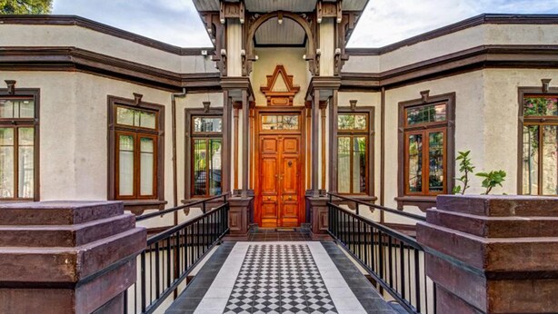Un edificio con fachada simétrica, una puerta central de madera y suelo a cuadros.