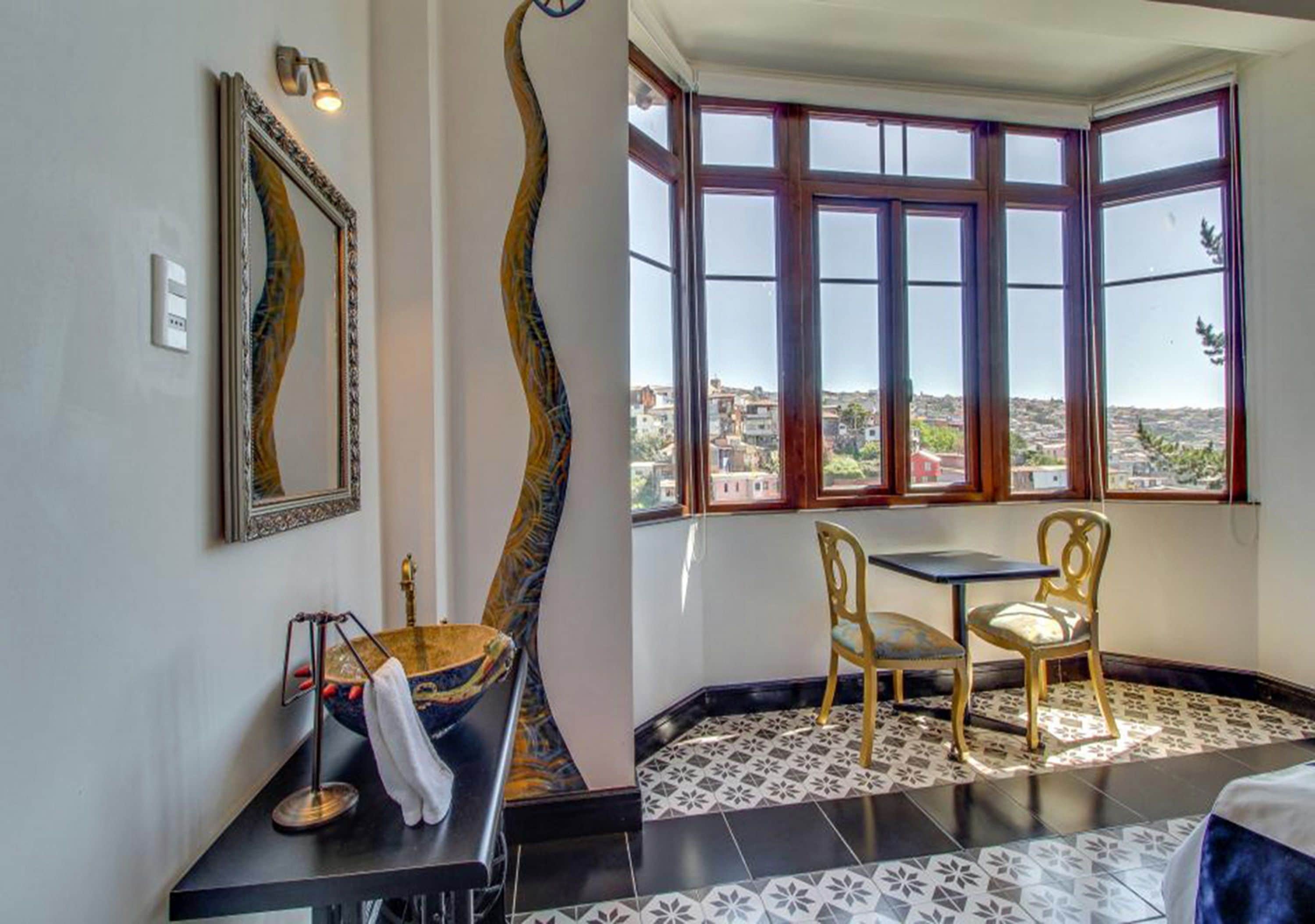 A room with a bay window, a black and white tiled floor, a gold-colored sink, and two chairs.