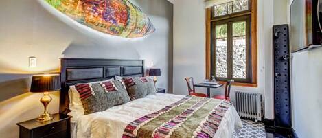 Un dormitorio con cama, mesitas de noche, ventana y radiador.
