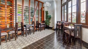 Un restaurante con una decoración moderna, que incluye una pared de botellas de vino, sillas de madera y vistas de la ciudad a través de grandes ventanales.