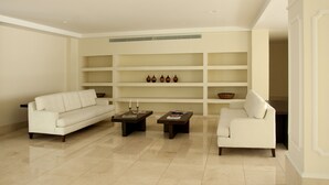 A modern living room with a white sofa, two coffee tables, and a bookshelf with decorative items. - Charming 3 Bedroom in the Old City (Cartagena)