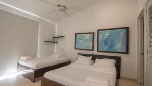 A hotel room with two beds, a ceiling fan, and artwork on the walls. - Charming 3 Bedroom in the Old City (Cartagena)