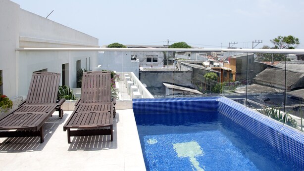 A rooftop swimming pool with lounge chairs and a view of the cityscape. - Charming 3 Bedroom in the Old City (Cartagena)