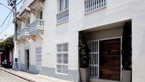 A white building with balconies, a wooden door, and potted plants. - Charming 3 Bedroom in the Old City (Cartagena)