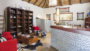A spacious room with a high ceiling, a wooden reception desk, a large bookshelf, and a red sofa.