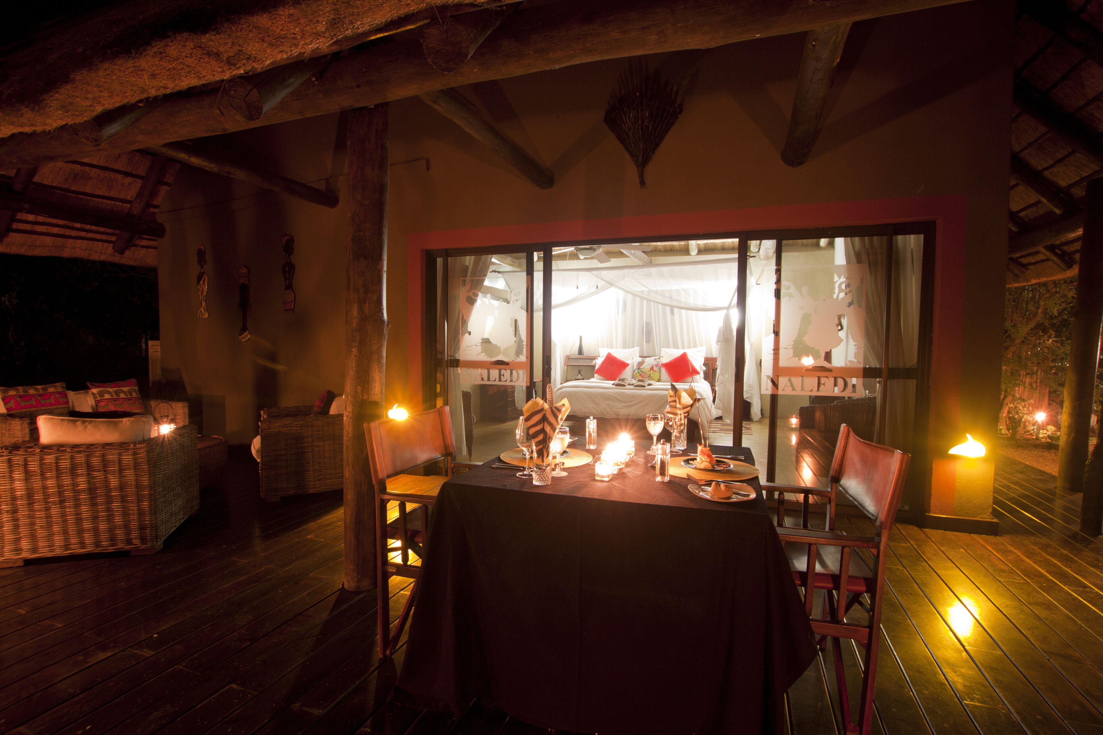 A dining area with a table set for two, wicker furniture, and candles.