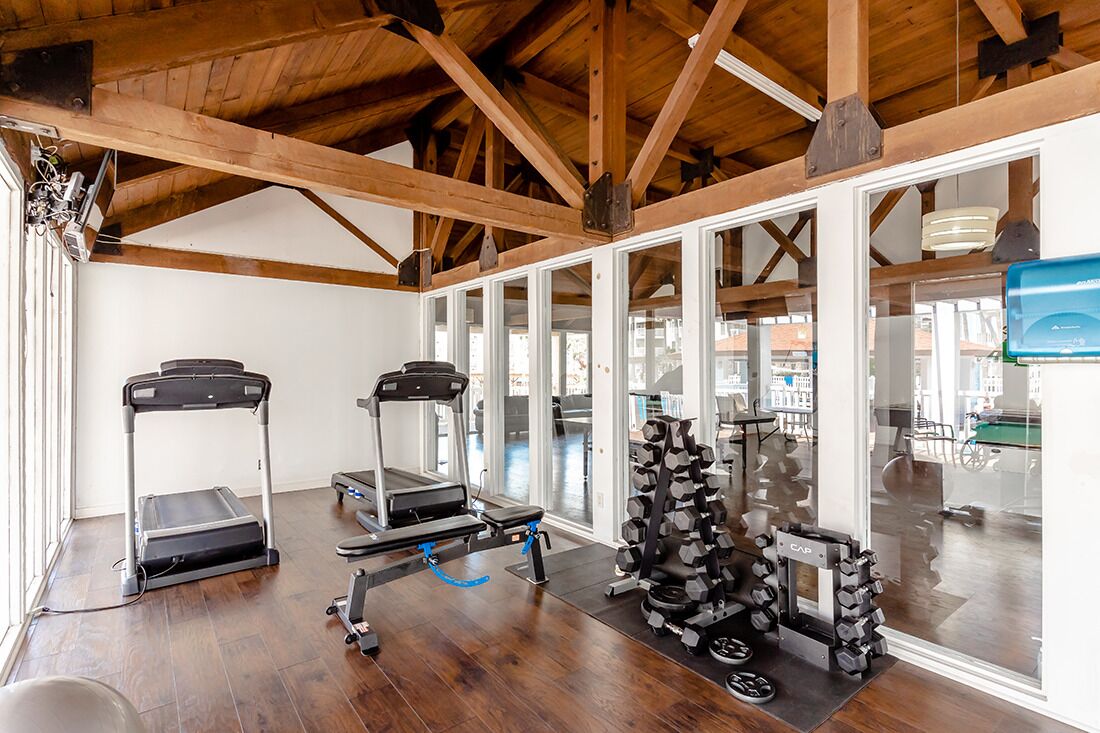 A gym with treadmills, a stationary bike, and a rack of dumbbells.
