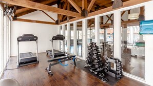 Un gimnasio con cintas de correr, una bicicleta estática y un estante con mancuernas.