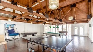 Amplio espacio interior con mesa de ping pong, mesa de billar y una silla plegable azul.
